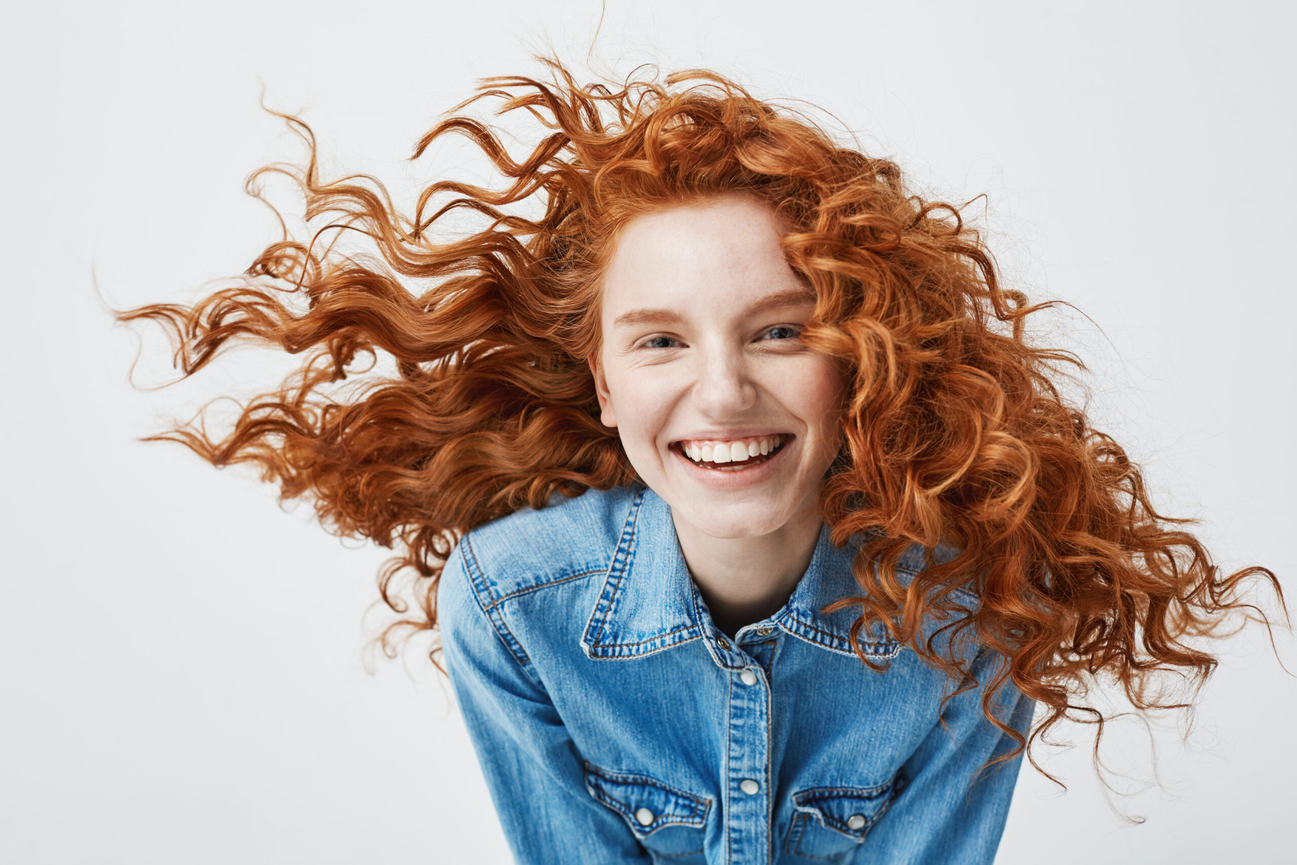 Portrait of beautiful cheerful redhead girl with flying curly hair smiling laughing looking at camera over white background. Portrait of beautiful happy cheerful redhead girl with flyingcurly hair smiling laughing looking at camera over white background.
